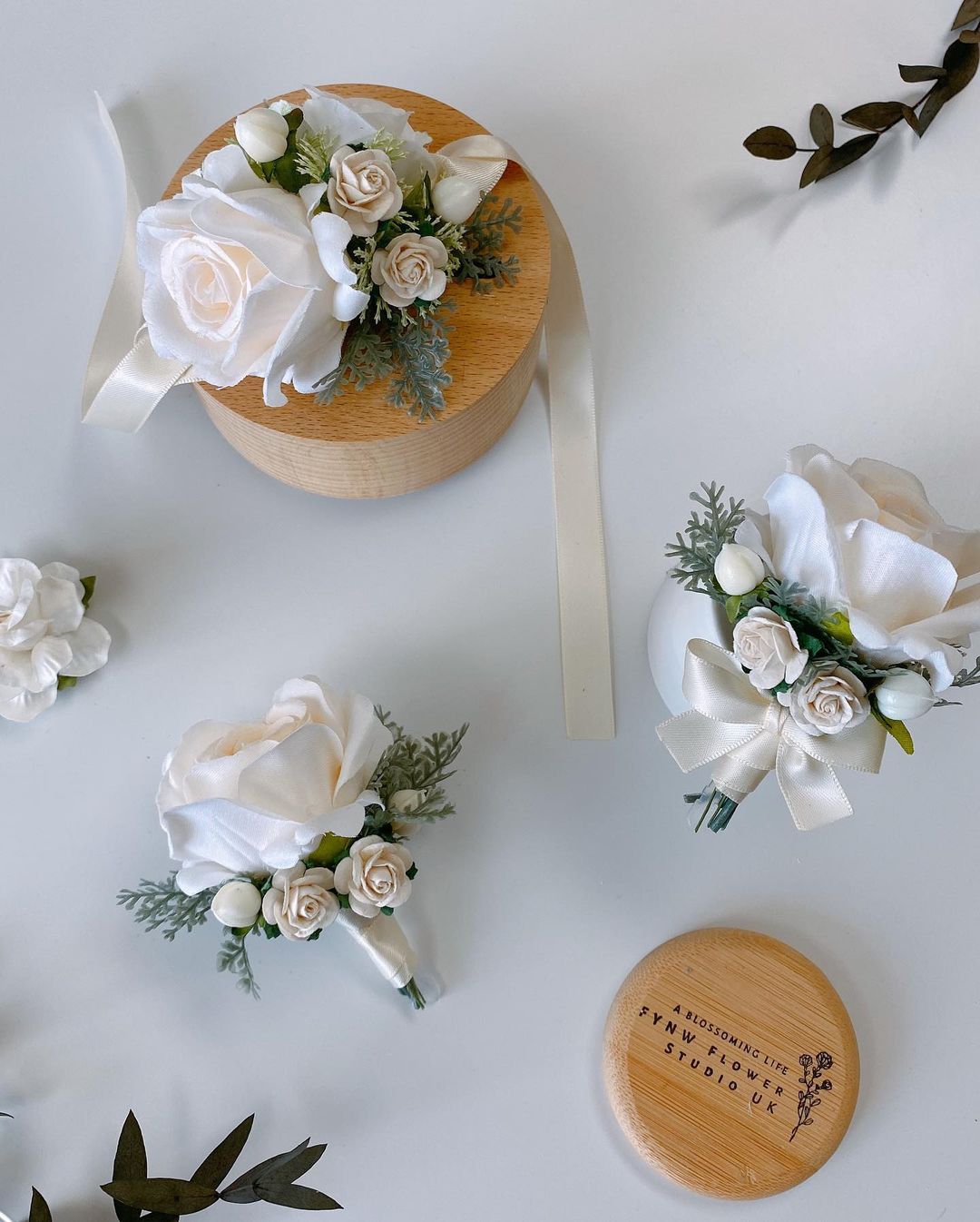 Eden Bridegroom Corsage Wedding Props -R220 is a corsage made of artificial flowers for weddings and other events. Corsage consists of white roses, violets and leaves and is adorned with a metal frame. Big enough for your guests to take pictures and keep. It&