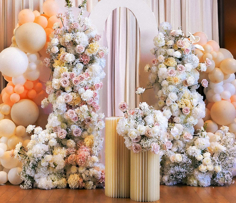 Blush floral arch with peach balloon garland at an indoor celebration