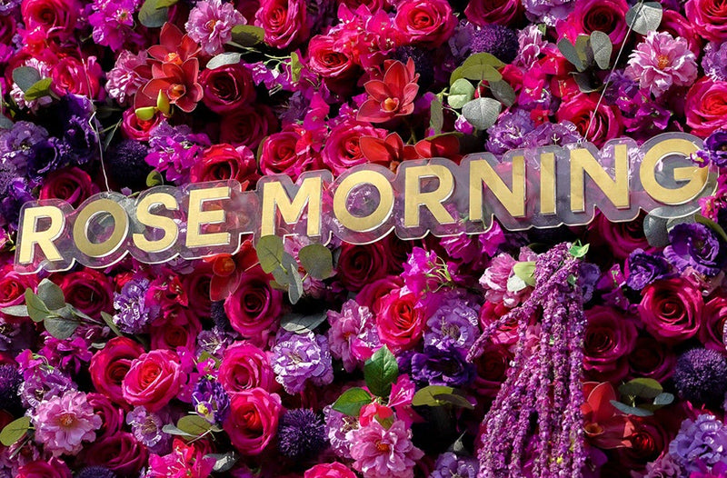 Gold Rose Morning lettering on a magenta and purple flower wall