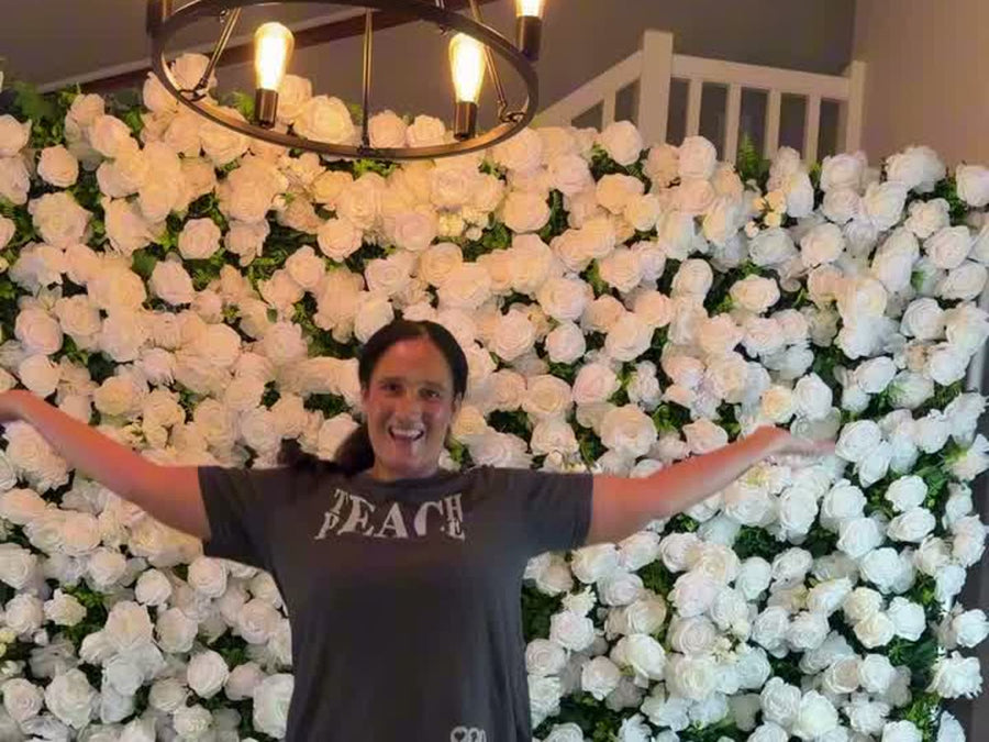 Wedding planner standing in front of an assembled white Rose Morning flower wall