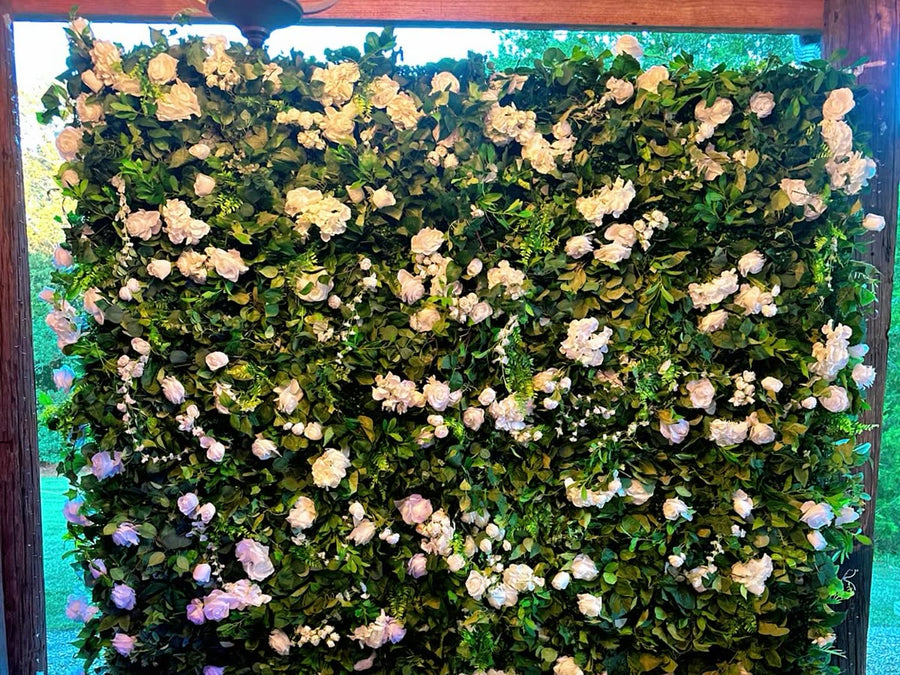 Greenery and white rose flower wall at a wedding venue