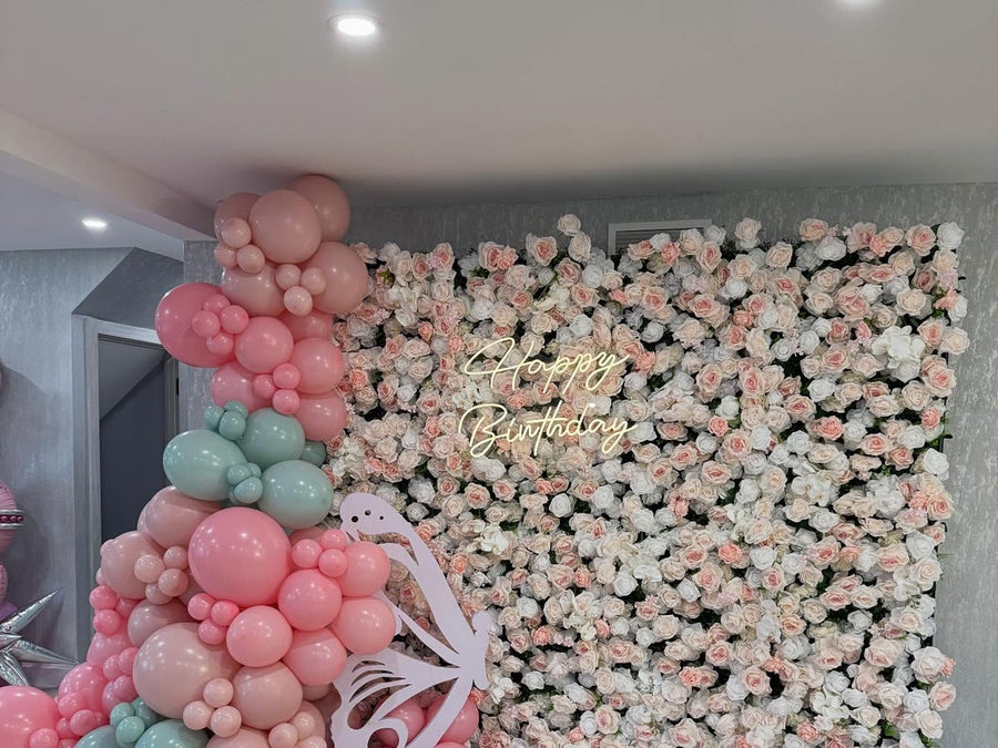 Blush flower wall with balloons and a Happy Birthday sign