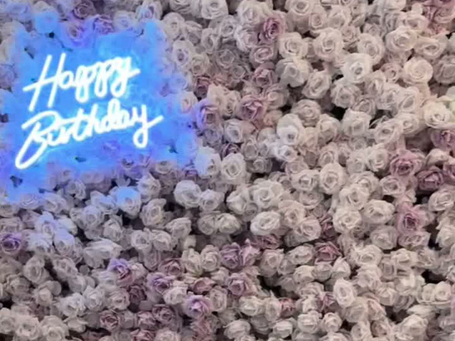 Lavender and white rose flower wall with a Happy Birthday neon sign