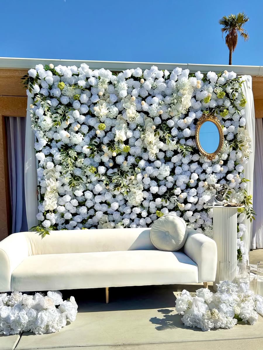 Outdoor lounge styled with a white flower wall and vintage details